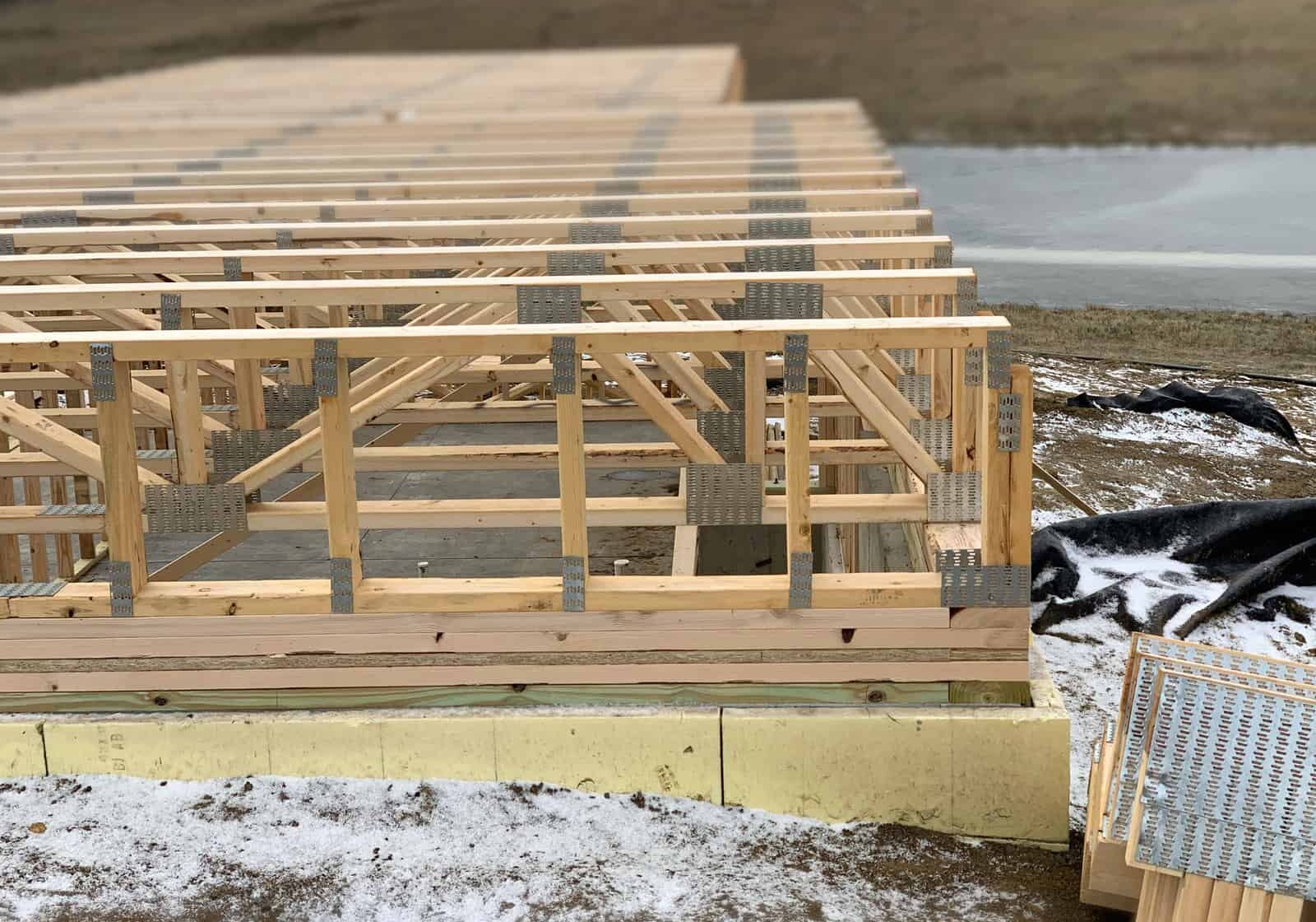 Open-web wood floor trusses installed over a foundation, connector plates visible