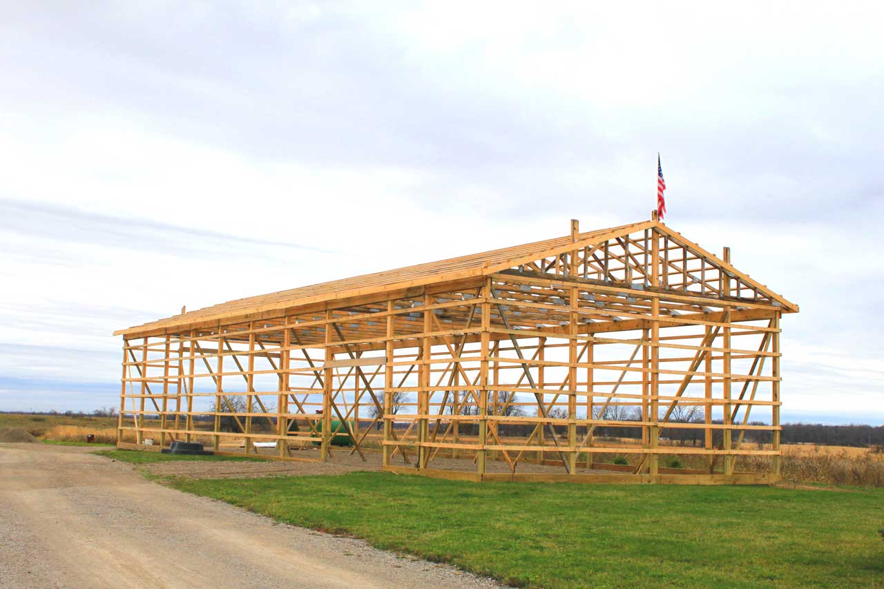 A pole barn frame under construction, with wood trusses spanning the full width