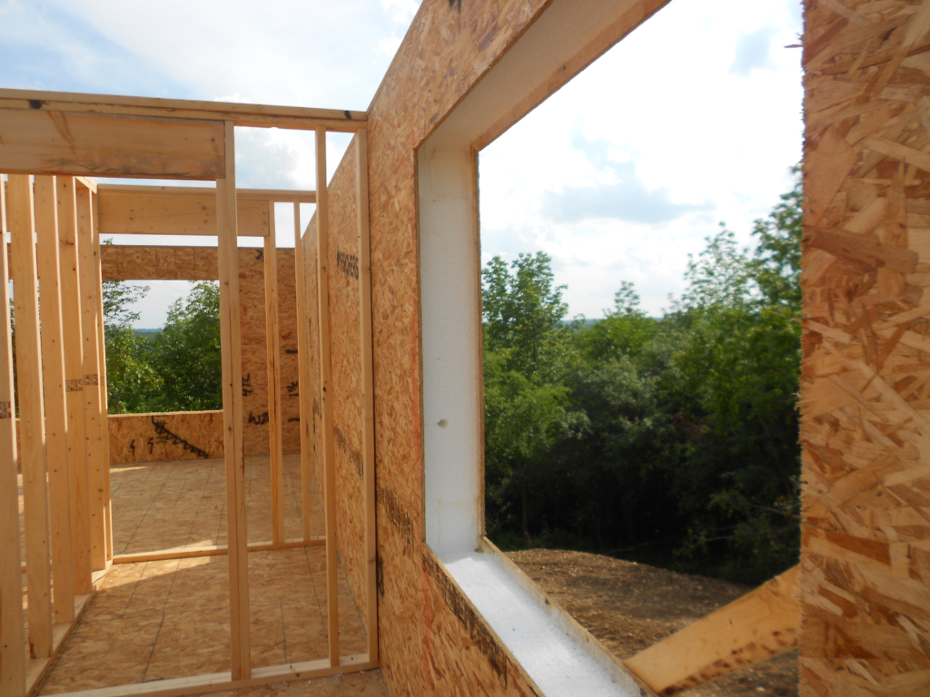 Structural insulated panel walls going up on a build, the foam core visible in a window opening